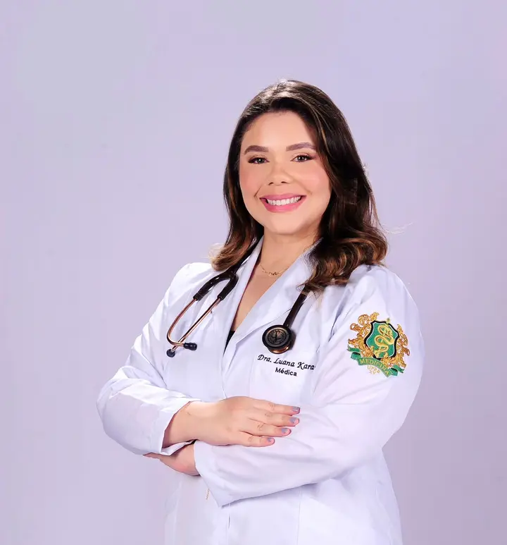Dra. Luana Karam, médica, de braços cruzados, jaleco branco